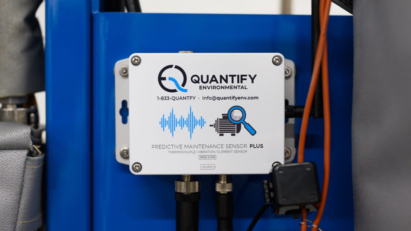 A Quantify predictive maintenance sensor on a blue machine frame beside orange power cabling