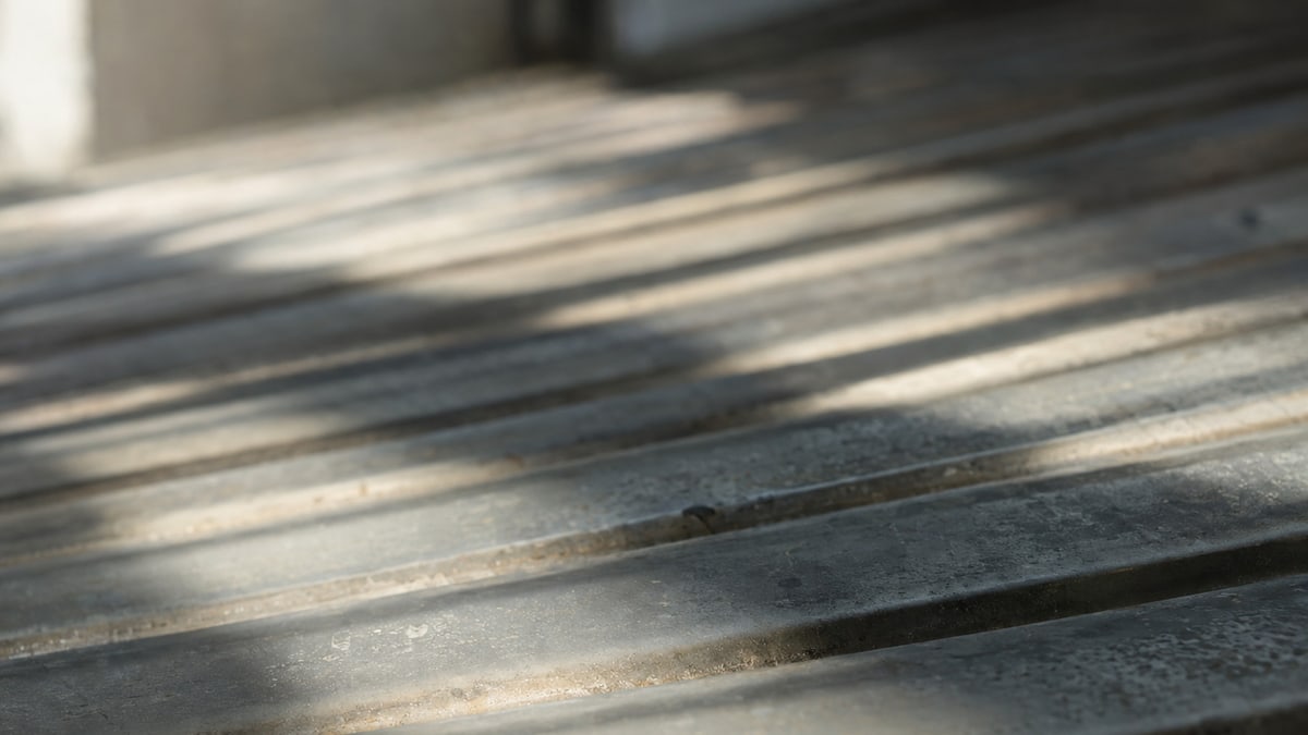 An abstract study: parallel shadows crossing ribbed metal and receding into focus blur