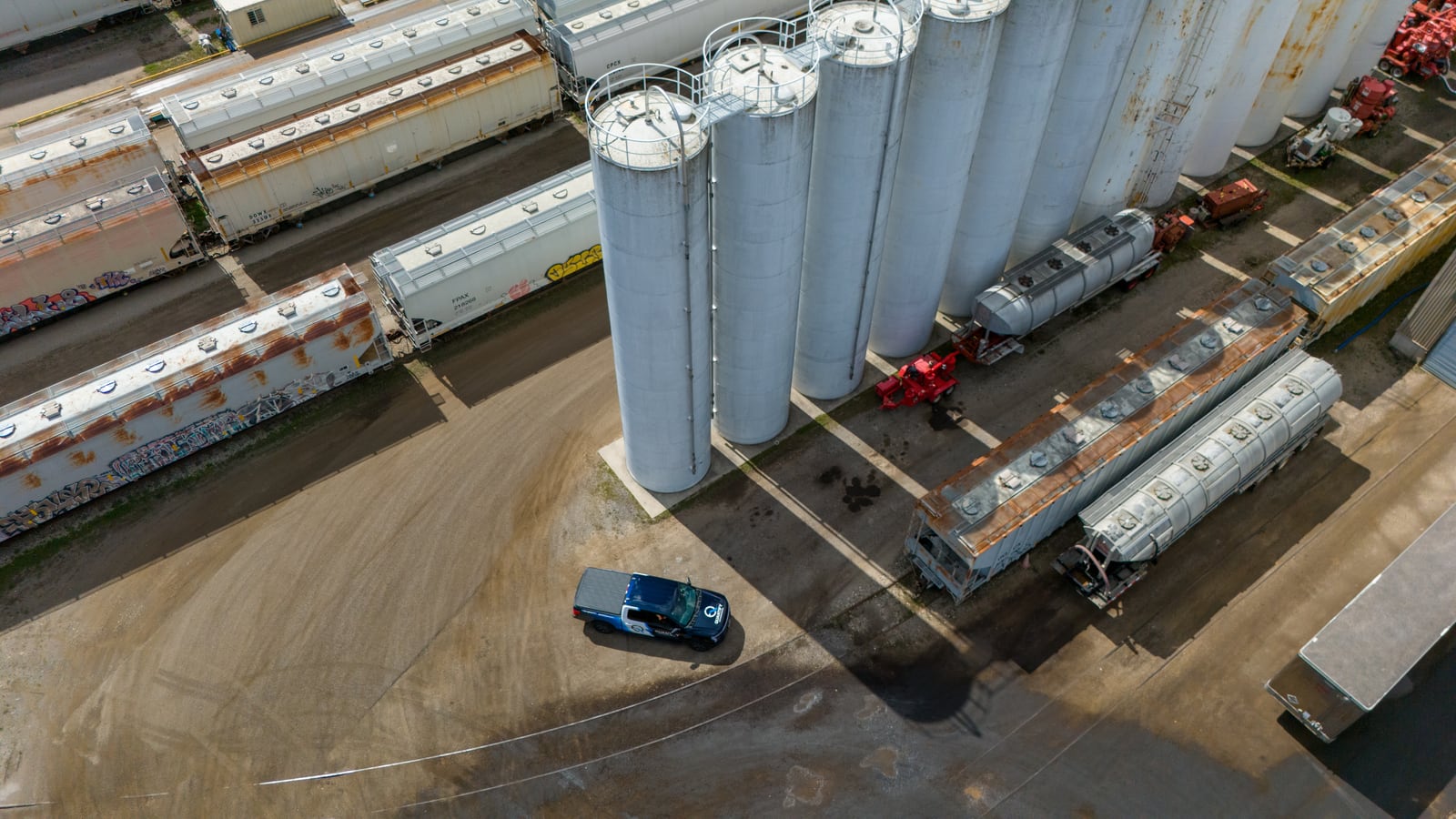 An aerial view of the Quantify truck on the apron beside a row of bulk storage silos and rail cars